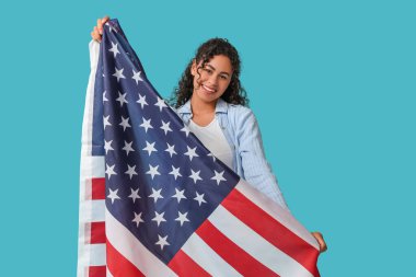 Mavi arka planda Amerikan bayrağı olan güzel, mutlu, Afro-Amerikan bir kadın.