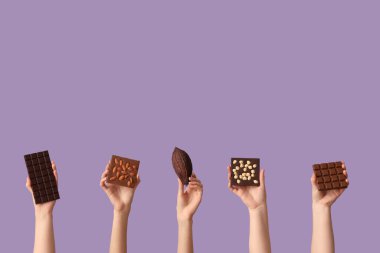 Farklı çikolata ve leylak arkaplanlı kakao kabuğu olan kadın elleri