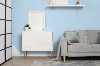 Gri kanepeli, beyaz çekmeceli ve raflı şık bir oturma odası, yakın plan.