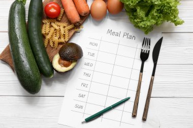 Sağlıklı ürünler ve beyaz ahşap arka planda haftalık yemek planı. Diyet kavramı