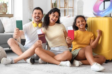 Pasaportları ve seyahat için bavulları olan mutlu bir aile evde oturuyor.