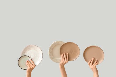 Açık arkaplanda boş tabakları tutan eller