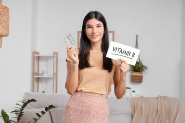 Evde B vitamini haplı genç bir kadın var.