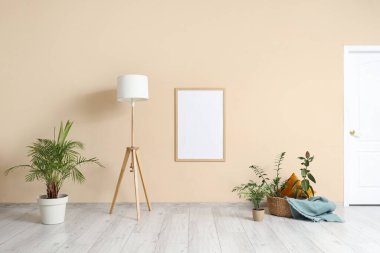 Yer lambası, hasır sepet ve oturma odasındaki bej duvarın yanında farklı bitkiler.