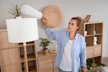 Evinde pp-toz temizleyici standart lambası olan olgun bir kadın.