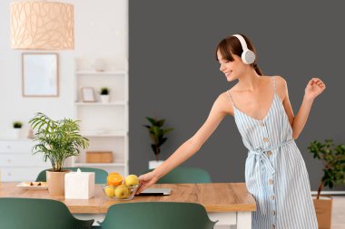 Yemek odasındaki masada kulaklıkları ve meyveleri olan genç bir kadın.