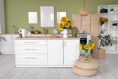 Beyaz tezgahları ve güzel ayçiçekleri olan şık bir mutfak.