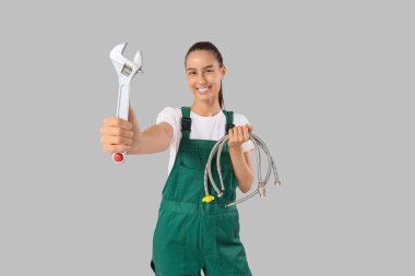 İngiliz anahtarı ve arka planda hortumları olan kadın tesisatçı.