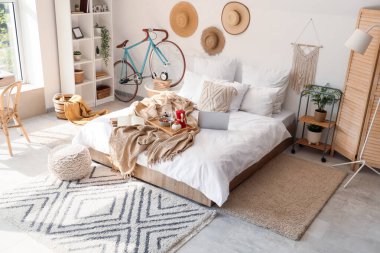 Yatak odasının içinde kahvaltı, kitap ve dizüstü bilgisayar var.