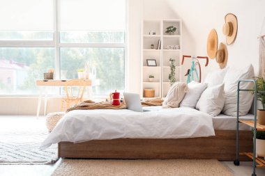 Yatak odasının içinde kahvaltı, kitap ve dizüstü bilgisayar var.