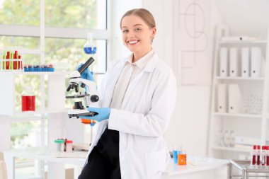 Laboratuvarda mikroskobu olan kadın kimyager.