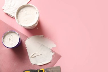 Pembe arka planda bıçak, eldiven, ağ ve macun kutuları.