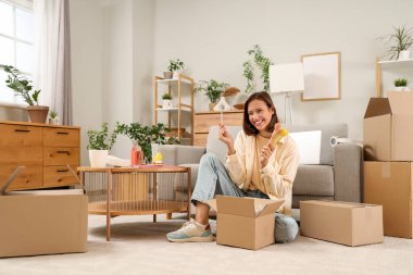 Güzel, genç, mutlu bir kadın evinde oturan bir sürü paketi açıyor.