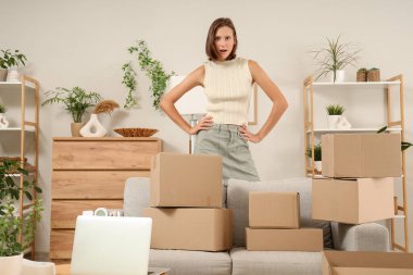 Dizüstü bilgisayarı ve evde bir sürü paketi olan genç ve güzel bir kadın.