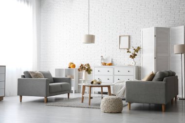 Sonbahar dekoru, kanepeleri ve çekmeceleri olan aydınlık oturma odasının içinde.