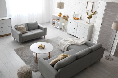 Sonbahar dekoru, kanepeleri ve çekmeceleri olan aydınlık oturma odasının içinde.