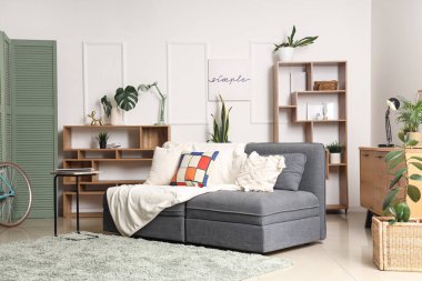 Oturma odasının içinde kanepe, bitki ve raf üniteleri var.