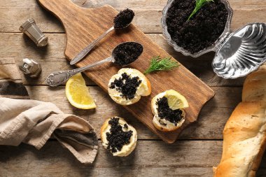 Deniz kabuğu şekilli yemek ve ekmek dilimleri ve ahşap zemin üzerinde lezzetli siyah havyar.
