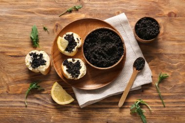 Ahşap arka planda lezzetli siyah havyarlı kâseler ve baget dilimleri