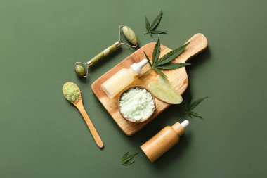 Deniz tuzu, masaj rulosu ve yeşil arka planda yapraklarla kenevir kozmetik yağı şişeleri.