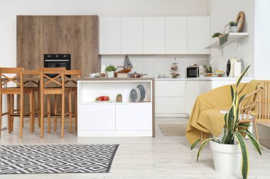 Beyaz tezgahlı, masa ve çatal bıçaklı modern mutfağın içi.