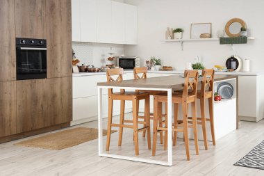 Beyaz tezgahlı, masa ve raflı modern mutfak.