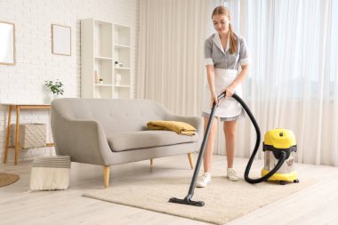 Genç hizmetçi odada süpürge temizliği yapıyor.