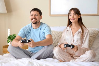 Pijamalı genç çift evde video oyunu oynuyor.