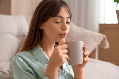 Evde pijamalı güzel bir kadın ve bir fincan kahve.