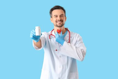 Tiroid bezi modeli ve mavi arka planda ilaç şişesi olan bir erkek endokrinolog.