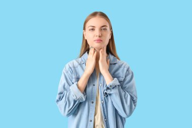 Mavi arka planda tiroid bezini inceleyen genç bir kadın.