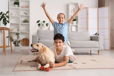 Mutlu kız ve erkek kardeş ve şirin Labrador köpeği evde yerde yatıyor.