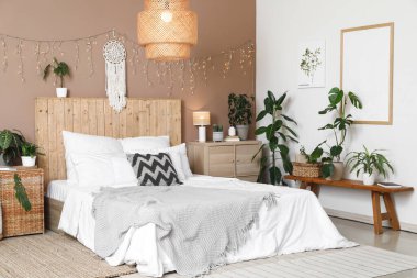 Şık bir yatak odası, farklı bitkiler, parlak bir çelenk ve büyük bir yatak.