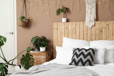 Şık bir yatak odası, farklı bitkiler, parlak bir çelenk ve büyük bir yatak.