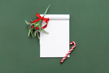 Yeşil arka planda ökseotu ve şeker kamışı oyuncağı olan defter