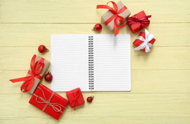 Noel hediyesi kutuları ve bej ahşap arka planda topları olan bir defter.