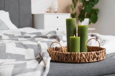 Yatak odasında yanan mumlar ve hasır tepsi.