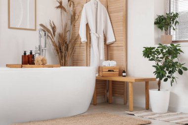 Banyonun içinde ahşap bank, küvet ve katlanır ekran var.