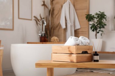 Aroma çubukları ve banyodaki bankta havluları olan tahta kutu.