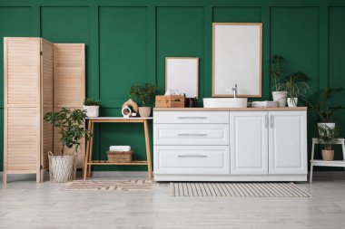 Tahta bank, çekmeceler ve banyoda yeşil duvarın yanında katlanan ekran.