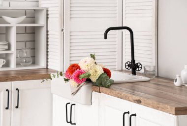 Mutfak tezgahındaki lavaboda bir buket güzel yıldız çiçeği.