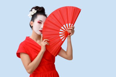 Işık arka planında yelpazesi olan güzel genç geyşa.