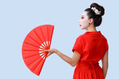 Işık arka planında yelpazesi olan güzel genç geyşa.