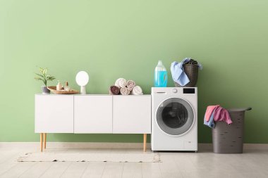 Modern çamaşır makinesi, çekmeceler ve çamaşır sepeti.