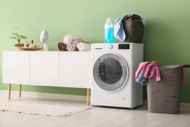 Modern çamaşır makinesi, çekmeceler ve çamaşır sepeti.