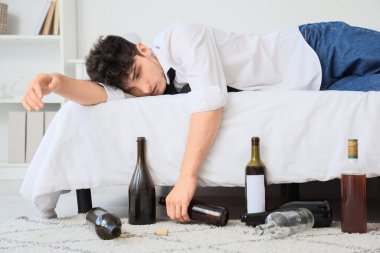 Sarhoş genç iş adamı yatakta yatıyor. Alkolizm kavramı