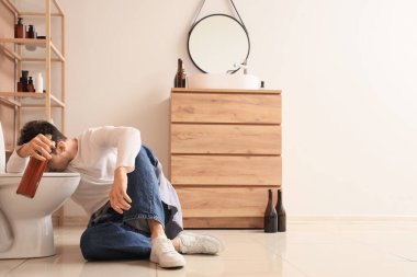 Akşamdan kalma hasta bir genç adam klozetin yanında. Alkolizm kavramı