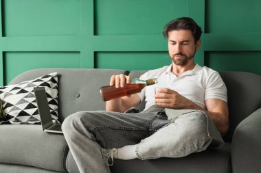 Kanepede oturan viski içen adam. Alkolizm kavramı