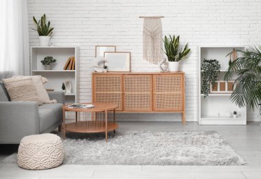 Oturma odasının iç tarafındaki beyaz tuğla duvarın yanındaki çekmece ve masa.