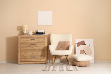 Beyaz koltuğu ve bej duvarın yanındaki şifoniyerde klasik daktilosu olan şık bir oturma odası.